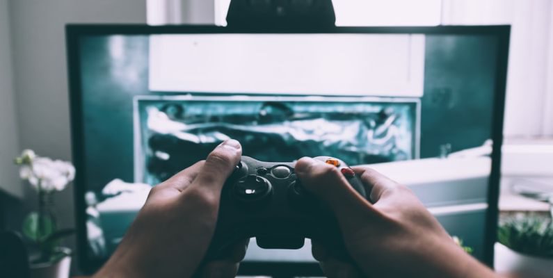 Affordable Entertainment - person holding game controller in-front of television