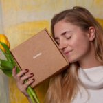 Beauty Box - woman in white sweater holding brown box and tulip flowers