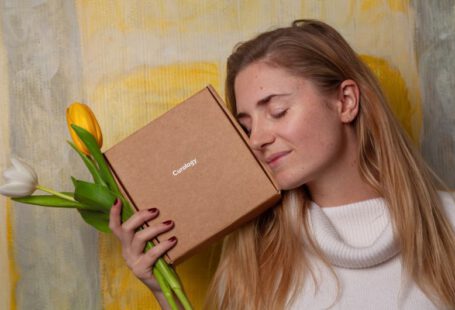 Beauty Box - woman in white sweater holding brown box and tulip flowers