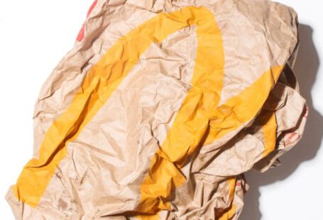 Eco Savings - Top view of crumpled empty craft paper bag of fast food restaurant placed on white background illustrating recycle garbage concept