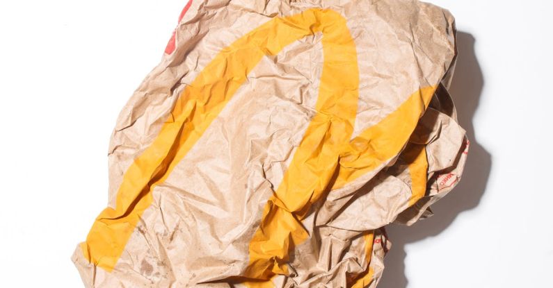 Eco Savings - Top view of crumpled empty craft paper bag of fast food restaurant placed on white background illustrating recycle garbage concept