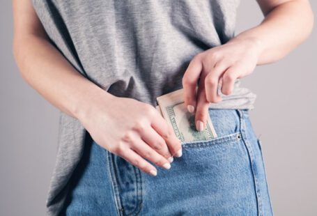 Fashion Savings - person in gray shirt and blue denim jeans holding blue denim jeans